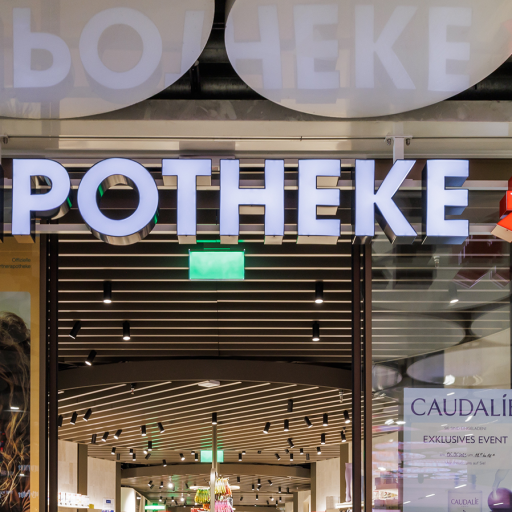 Beleuchtetes Apotheke-Schild mit grünem Kreuz am modernen Pharmacy-Eingang im Einkaufszentrum.